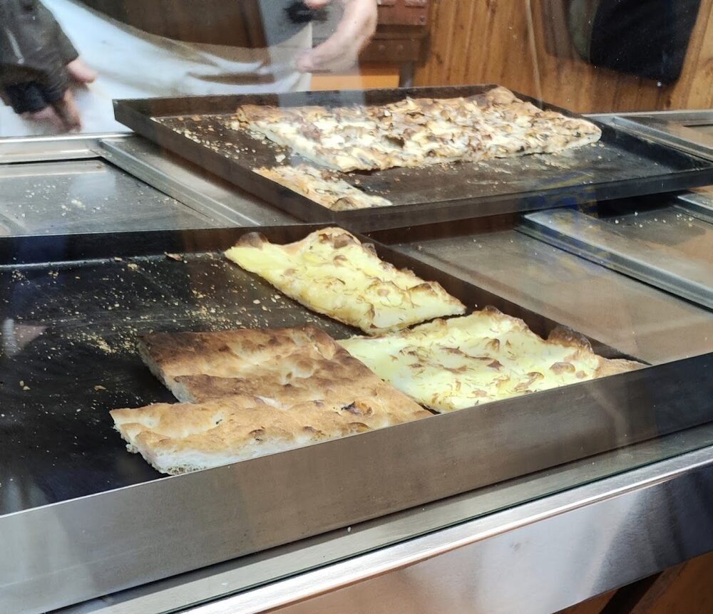 Il banco di PizUp con le teglie di pizza sotto il vetro.