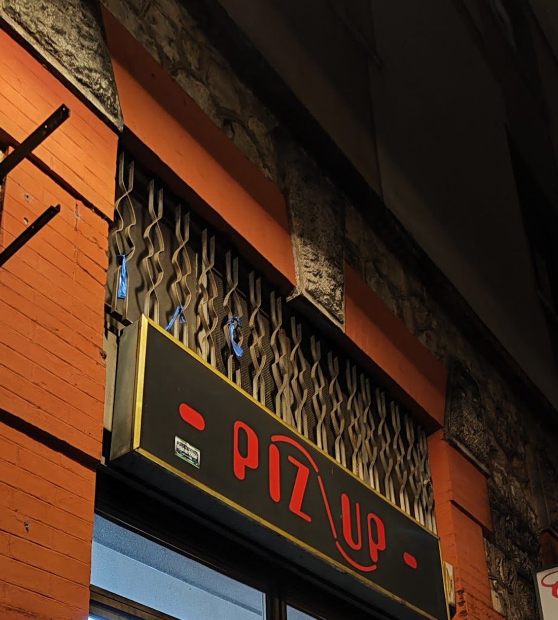 L'insegna illuminata di PizUp sopra l'ingresso, in Viale Guglielmo Marconi.