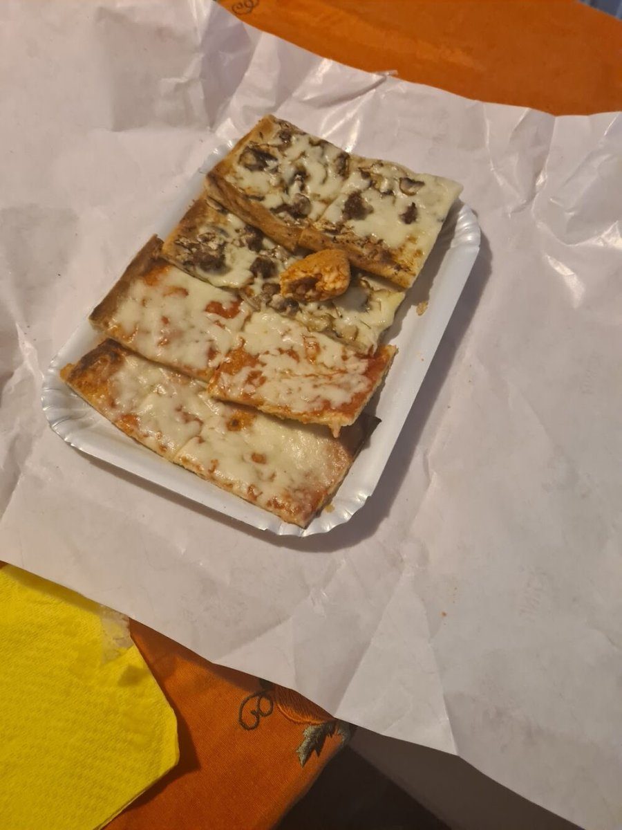 Tranci di pizza al taglio appoggiati sulla carta.